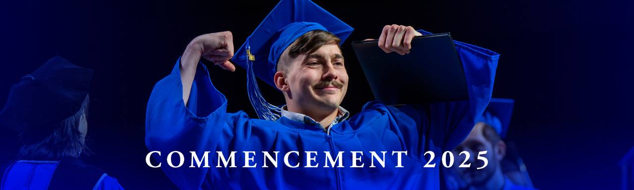 graduate smiling and flexing arms wearing blue cap and gown